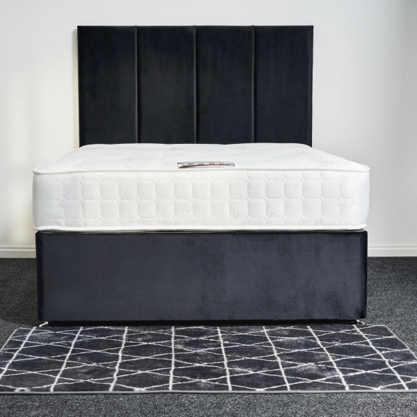 Bed with white mattress and black headboard on a gray floor with a geometric pattern.
