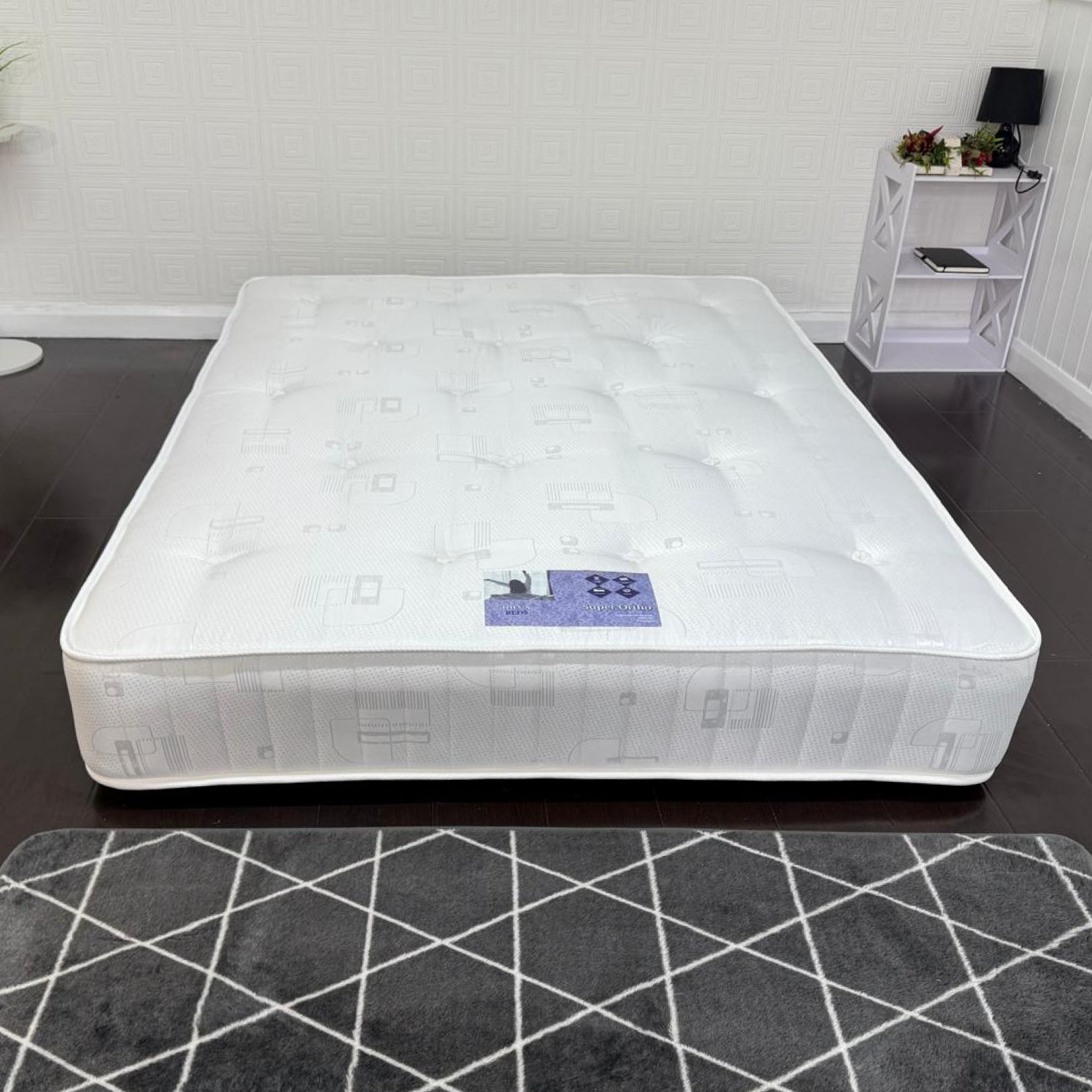 White mattress on a dark floor with a white wall background