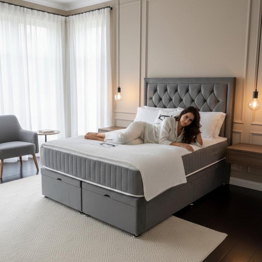 Woman lying on a gray upholstered bed in a modern bedroom.
