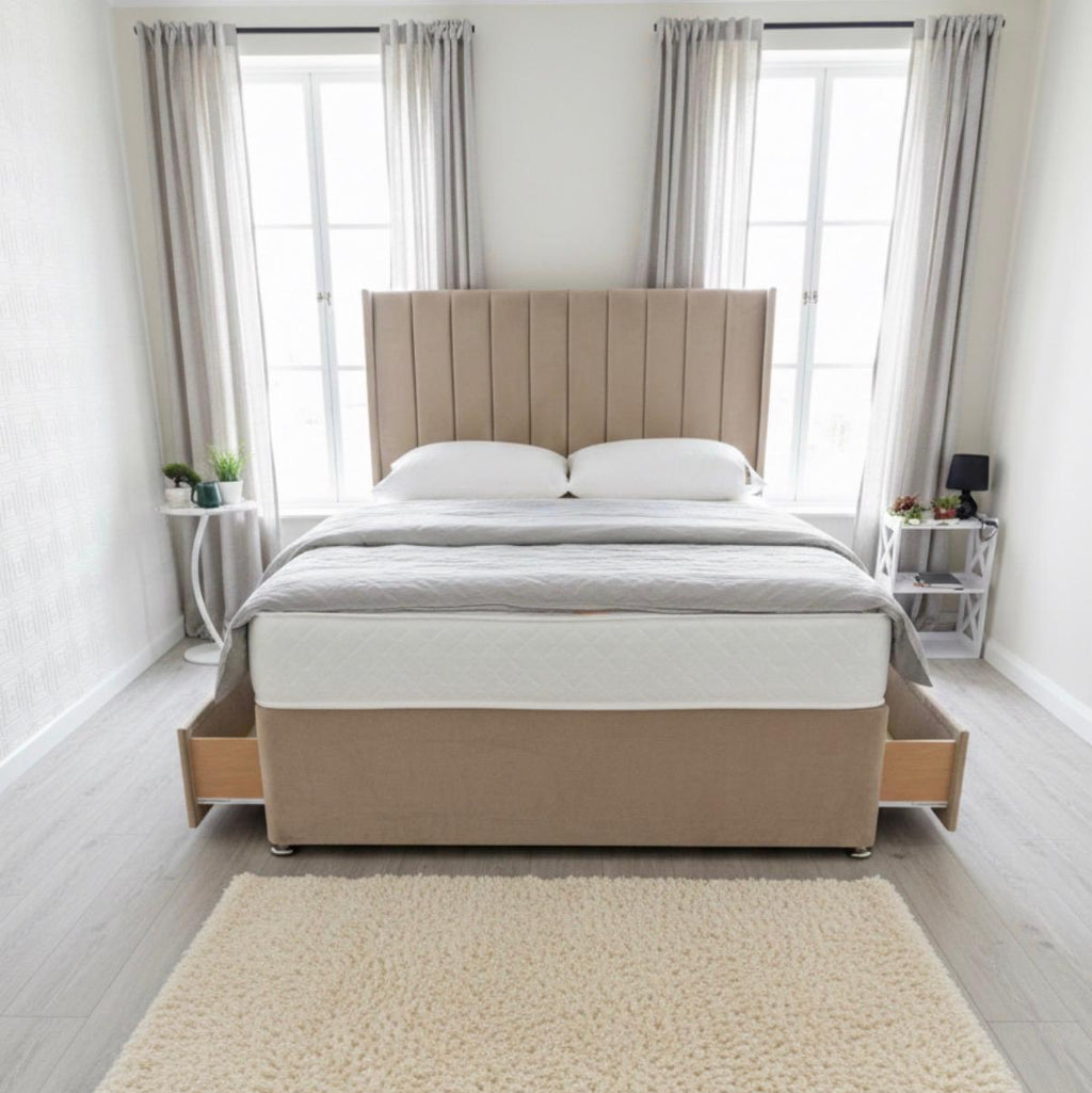 Beige upholstered bed in a bright bedroom with large windows and light decor.