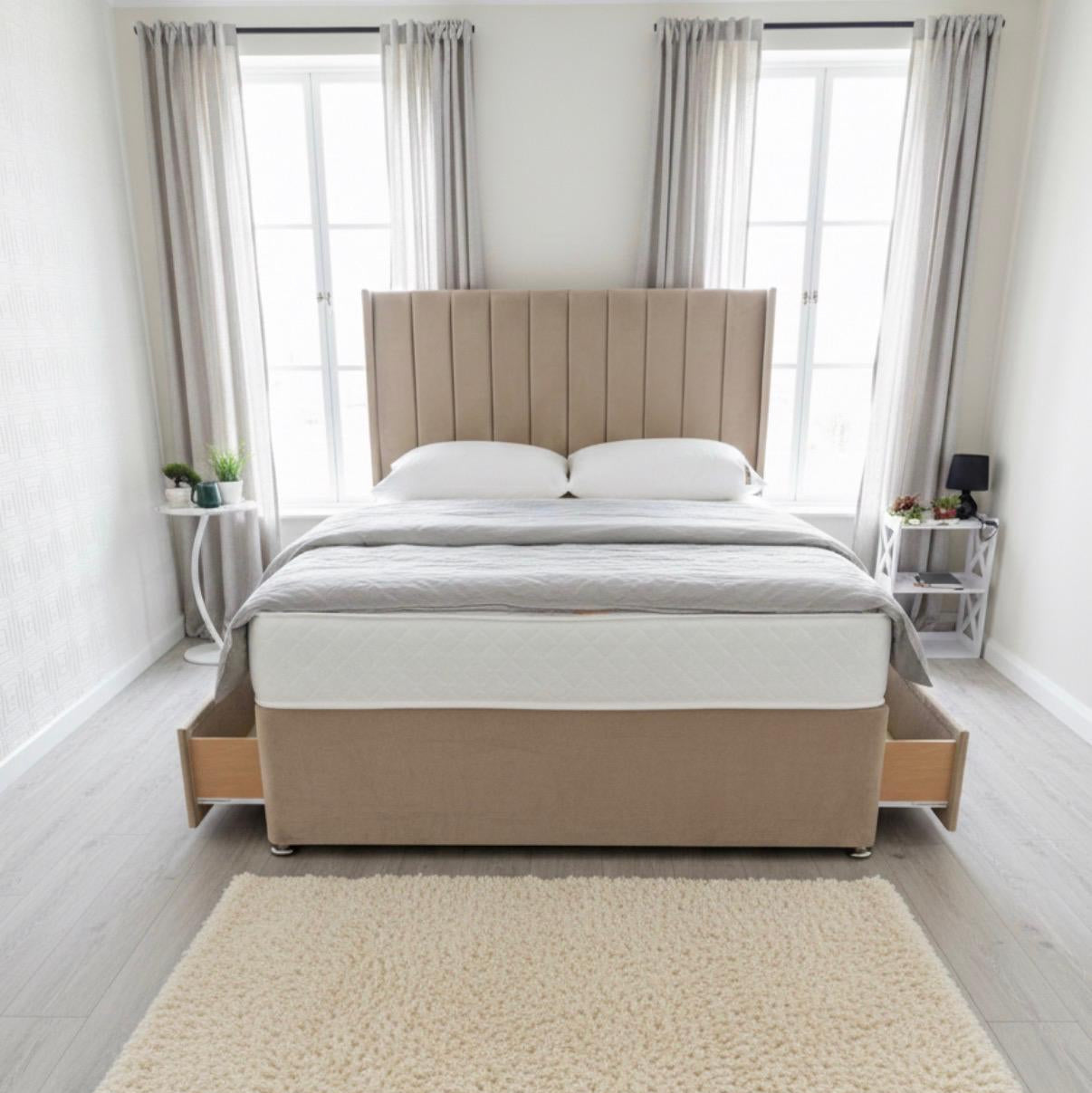 Beige upholstered bed in a bright bedroom with large windows and light decor.