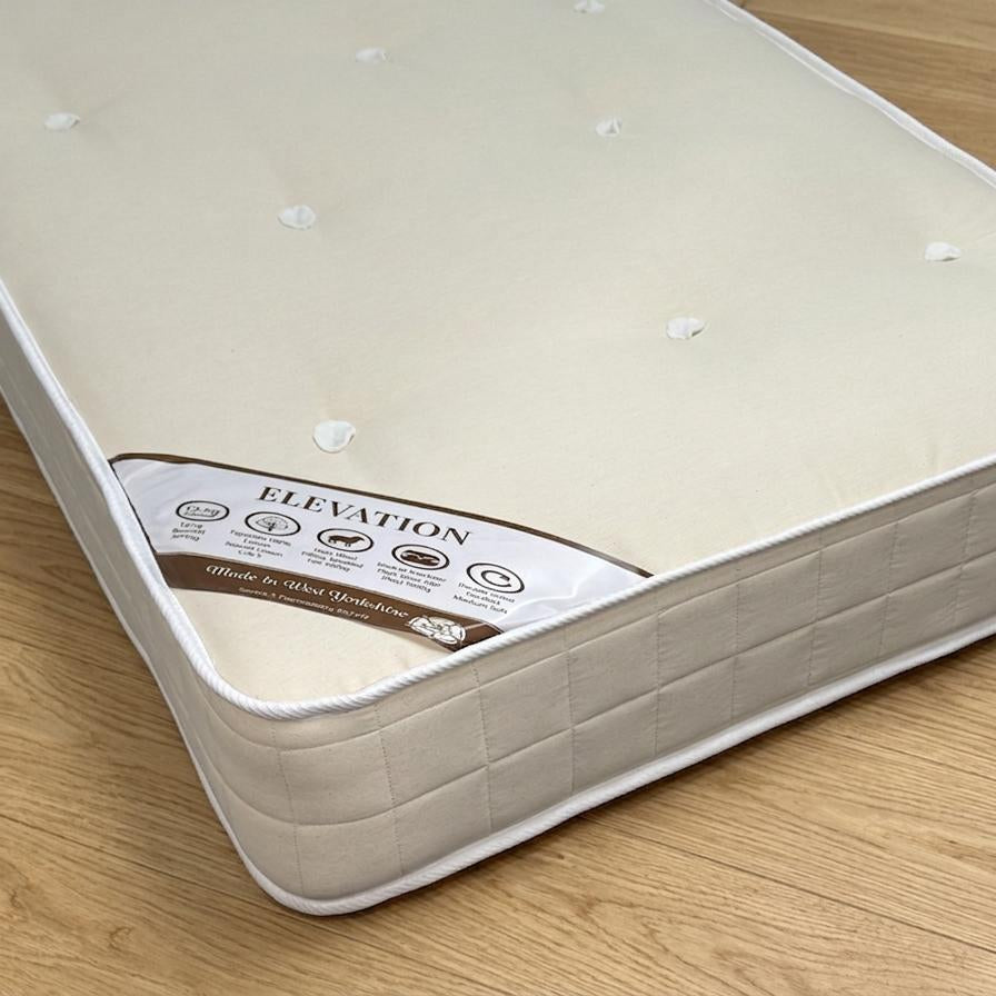 Beige mattress on a wooden floor with 'Elevation' branding.