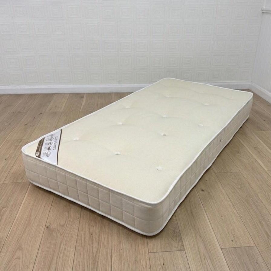 Mattress on a wooden floor with a white wall background