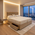 Beige bed with storage drawers in a modern bedroom with cityscape view