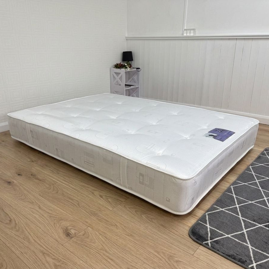 White mattress on a wooden floor with a gray rug