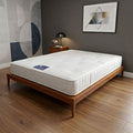 Mattress on a wooden bed frame in a room with abstract wall art and a lamp.
