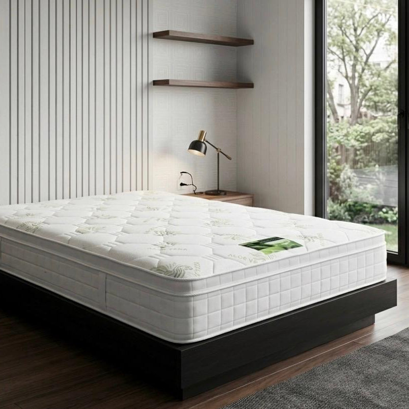 White mattress on a wooden bed frame in a modern bedroom with large windows.