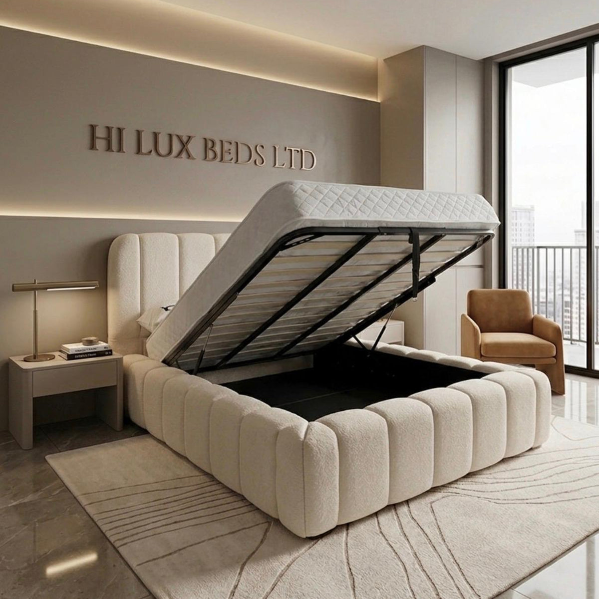 A modern beige upholstered lift-up storage bed with its gas-lifted frame raised, showing the storage compartment underneath. The bed is set in a luxury bedroom with a matching headboard, a side table, a lamp, and a brown armchair, with the brand name 'HI LUX BEDS LTD' displayed on the wall.