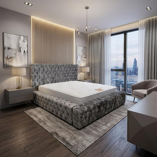 A modern bedroom featuring a low, tufted platform bed with a gray patterned upholstered frame and a white mattress. The bed is set on a textured gray area rug over dark wood flooring, with a vertical slatted wood accent wall and warm LED strip lighting behind the headboard.