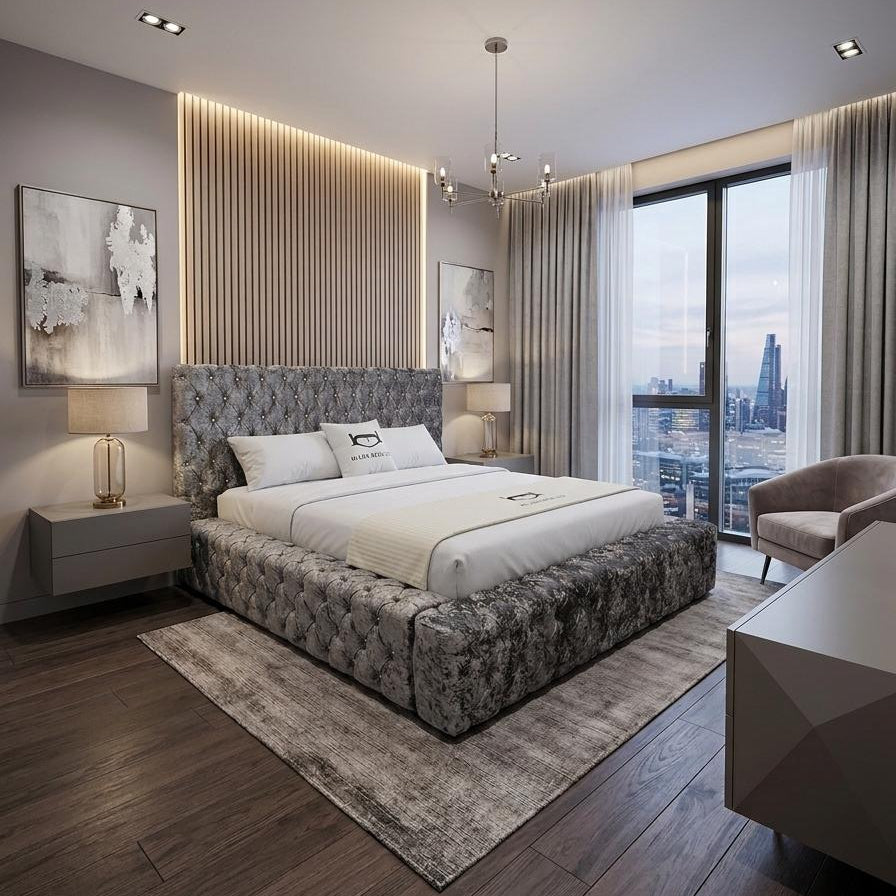 A modern bedroom featuring a high platform bed with a tufted gray and white upholstered headboard and footboard, dressed in white bedding. The room has dark wood floors, a textured gray rug, a slatted wood accent wall with warm LED lighting, and a large window overlooking a city skyline.