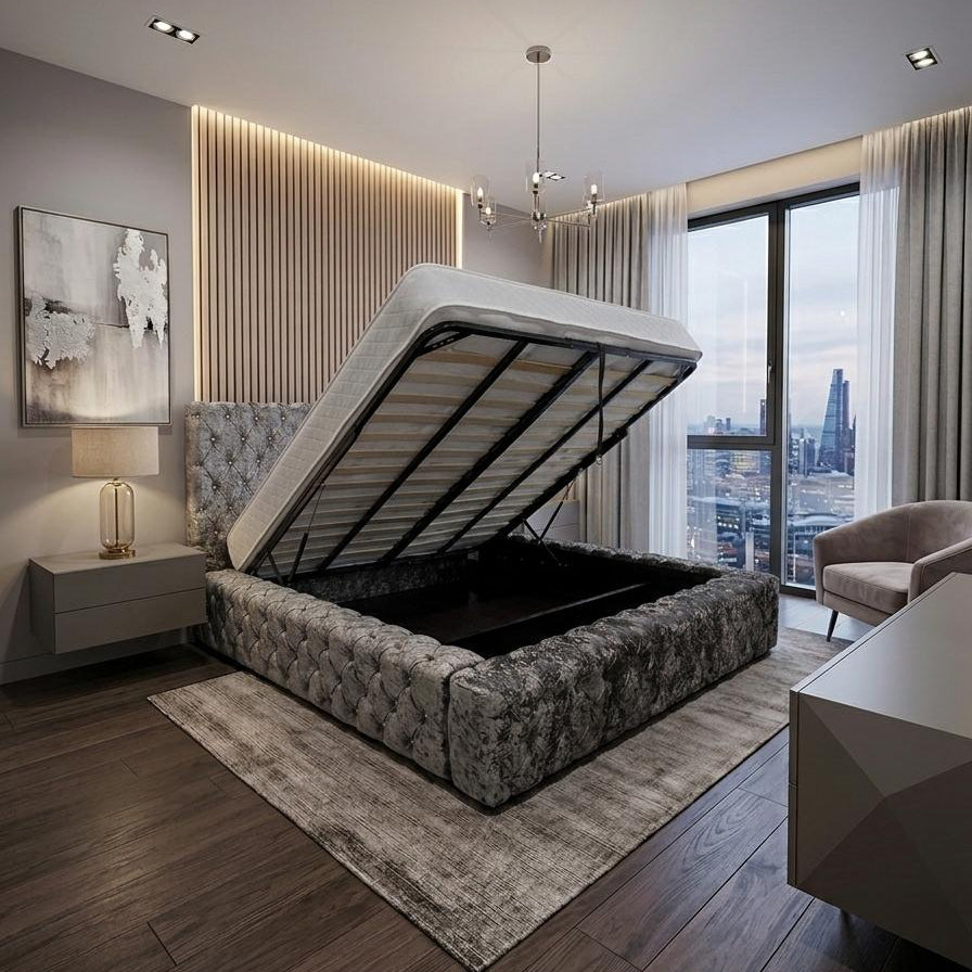 A modern bedroom featuring a low-profile platform bed with a raised gas-lifted mattress base, shown in an open position to display the storage compartment. The bed has a textured gray and white floral patterned upholstered frame, set on a gray area rug over dark wood flooring.