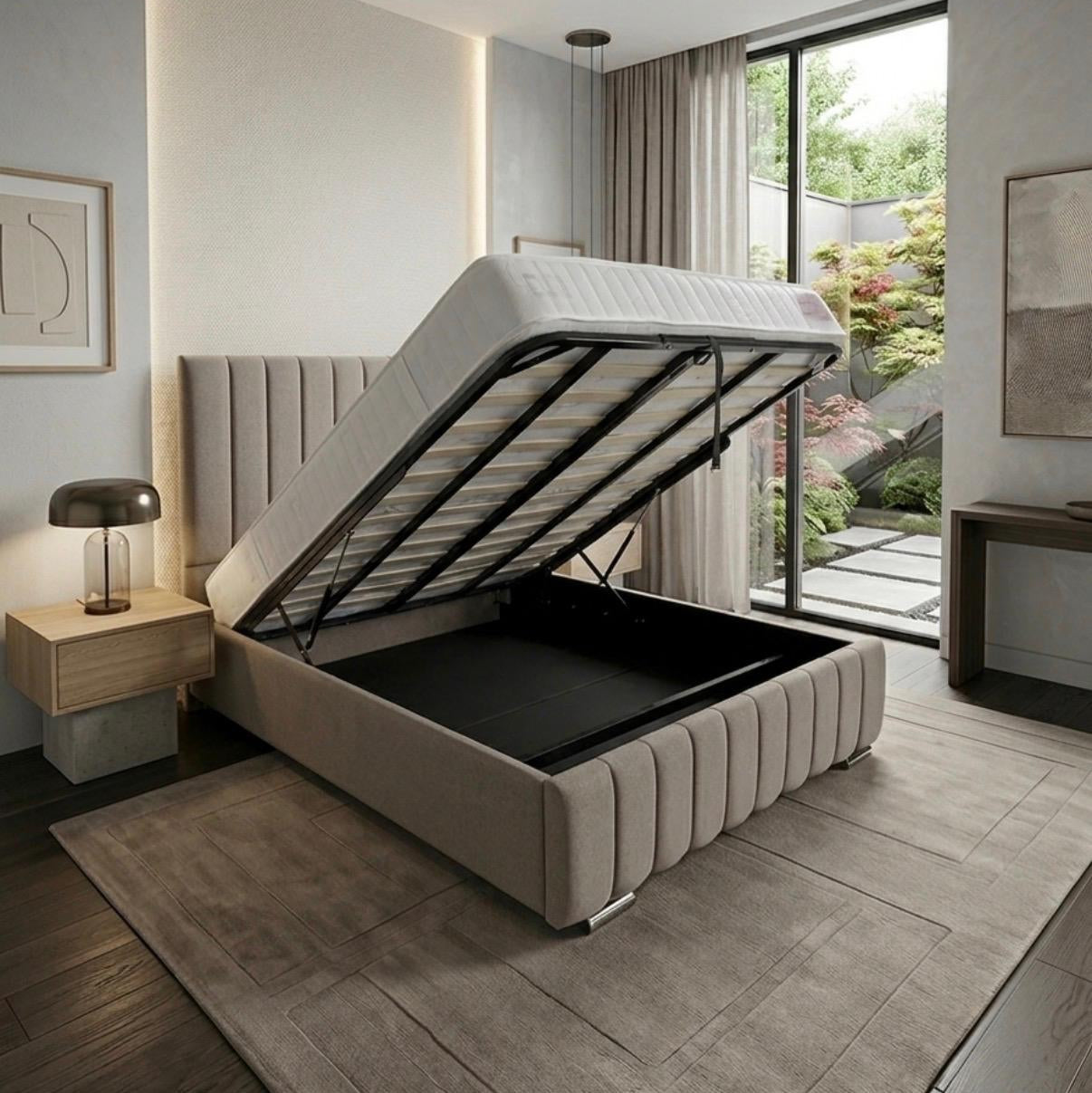 A modern upholstered storage bed with the mattress lifted open to reveal a black storage compartment, shown in a styled bedroom interior with a window, rug, and bedside lamp.