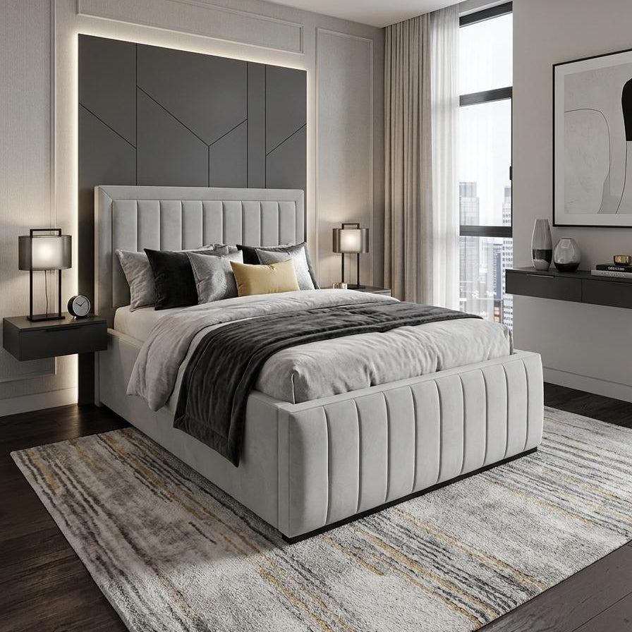 A modern bedroom featuring a light gray tufted upholstered bed frame with a matching headboard, styled with gray and black bedding, a gray patterned rug, and contemporary wall lighting.