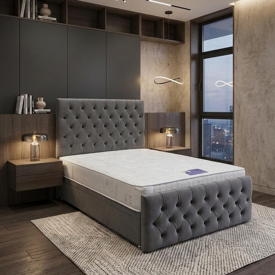 A modern gray tufted bed frame with a white mattress, styled in a contemporary bedroom with dark wood nightstands, a textured rug, and a large window.